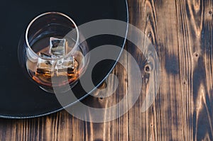 Glass of brandy with ice cubes/Glass of brandy with ice cubes on a black tray. Top view and copyspace