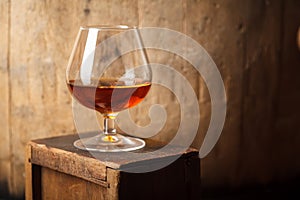 Glass of brandy near a barrel