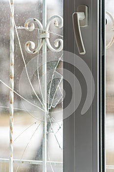 Glass broken by hooligans in a metal-plastic window, close-up