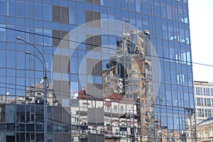 The glass building reflects buildings on the opposite side.