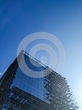 A glass building under construction. Blue sky. Construction. Modern architecture