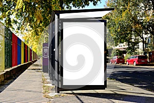 Glass bus shelter at a busstop. empty ad panel and billboard sign