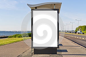 Glass bus stop by the sea, with a white advertising space. Blank billboard and outdoor advertising. Mockup poster