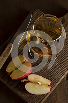 Glass of Calvados Brandy and red apples on wooden table