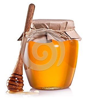 Glass can full of honey and wooden dripper on a white. photo
