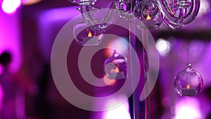 Glass candlestick on the banquet table, decorative candlestick, shallow depth of field, blurred silhouettes of people