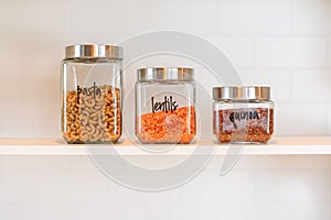 Glass canisters lined up on a kitchen shelf