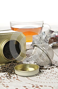 Glass cap of tea and organic black tea in metal can