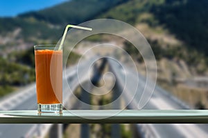 A glass of carrot juice in the cafe with view on a speed highway through the window
