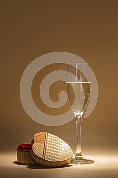 Glass of cava and an open box, it is shaped like a heart. the atmosphere is intimate