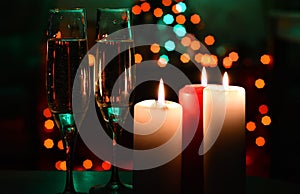 Glass of champagne and candles on bokeh background