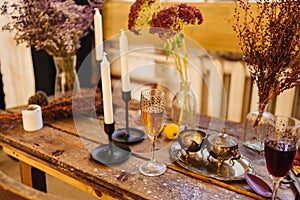 a glass of champagne, candles and silverware on a wooden table.