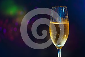 A glass of champagne on the right side of the frame on a multi-colored blurry background