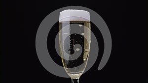 Glass of champagne with a rotating bubbles inside. Black background. Close up