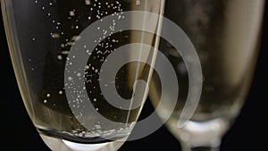 Glass of champagne with a rotating bubbles inside. Black background. Close up