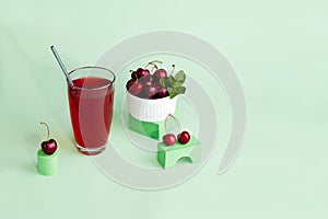A glass of cherry cocktail, a bowl with berry. Fresh cold refreshing summer drink with cherry and ice