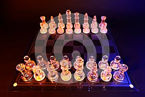 Glass chess on a chessboard lit by blue and orange light