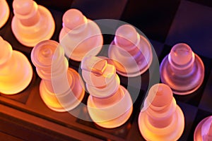 Glass chess on a chessboard lit by blue and orange light