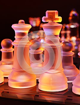 Glass chess on a chessboard lit by blue and orange light