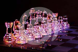 Glass chess on a chessboard lit by blue and orange light