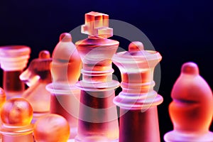 Glass chess on a chessboard lit by blue and orange light