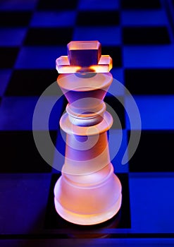 Glass chess on a chessboard lit by blue and orange light