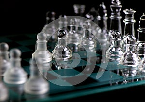 glass chess pieces are defending the king on board in dark