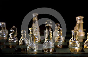 Glass chess pieces are defending the king on board in dark