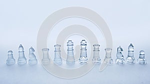 Glass chess pieces in a row on a white background