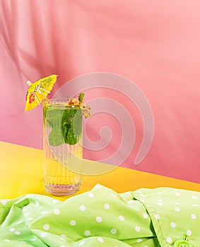 Glass of chill sparkling water, mojito cocktail with fresh mint, lime and rom isolated on pink background. Summer drink.