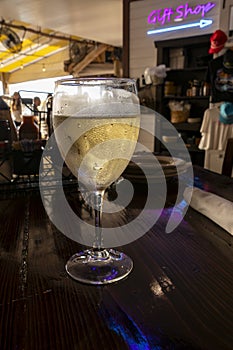 A Glass of Chilled White Wine on the Table of a Lively Restaurant photo