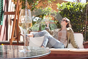 glass of chilled white wine on table over young woman and Tuscany backgound