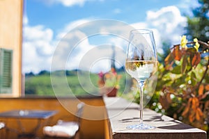 Glass of chilled white wine on a Tuscany background. Agriturismo vacation in Italy