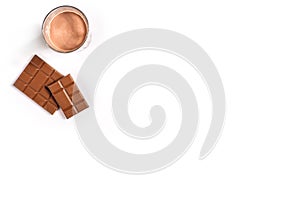 Glass of chocolate milk with chocolate bar on white background with space for text or design. Top view photo