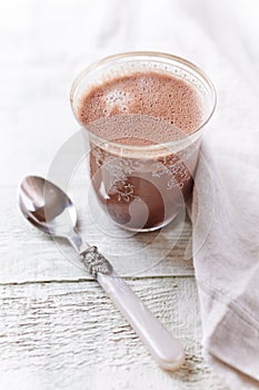 Glass of chocolate milkshake on bright wooden background