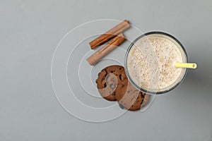Glass of chocolate milkshake, cookies and cinnamon on gray background