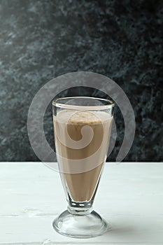 Glass of chocolate milkshake on white wooden table