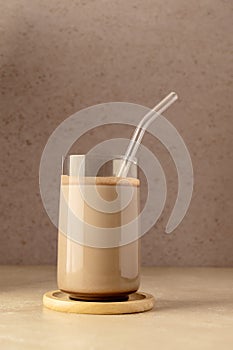 Glass of chocolate shake drink with protein powder scoop and glass straw.