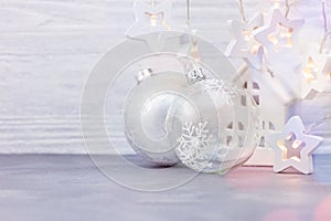 Glass christmas balls, star garland lights and small house toy on white background