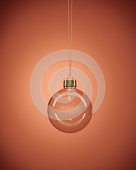 Glass christmas bauble hanging in front of luxury dark orange background