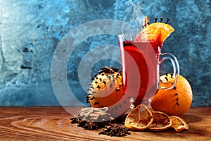 Glass of christmas hot mulled wine on wooden table with species and oranges against frozen window.Copy space