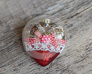 Glass Christmas toy on a wooden background. A heart. quadratic