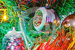 Glass christmas toys on the branches of decorative fir in the light of colorful lights of electric garland