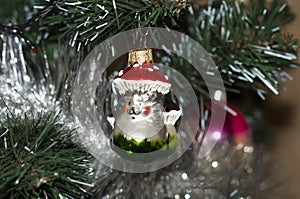 a glass Christmas tree toy in the form of a fairy-tale hedgehog hanging in a tree