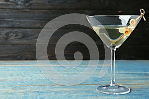 Glass of Classic Dry Martini  olives on light blue wooden table against dark background. Space for text