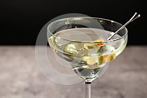 Glass of Classic Dry Martini  olives on table against black background, closeup
