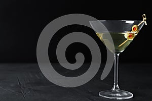 Glass of Classic Dry Martini with olives on table against black background. Space for text