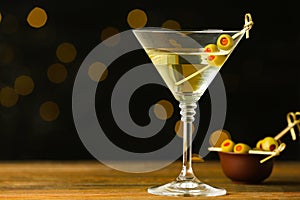 Glass of Classic Dry Martini with olives on table against blurred background. Space for text