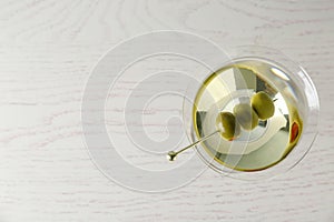 Glass of Classic Dry Martini with olives on wooden table, top view