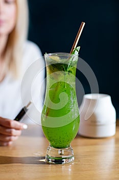 Glass with classic mojito cocktail with lemon and mint, cold refreshing drink or beverage with ice on bright marble